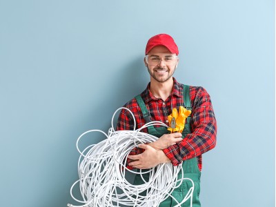 Technieker met kabels in zijn armen, blij omdat hij dankzij de opleiding van Syntra nu alles weet over Electro-Techniek